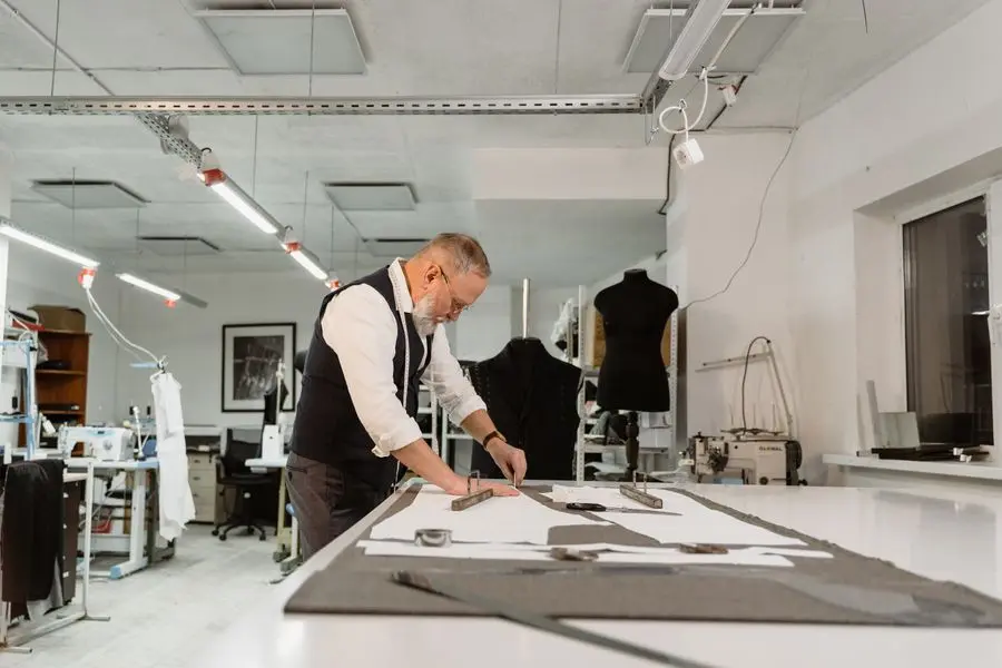 A pattern maker drafting at the studio table